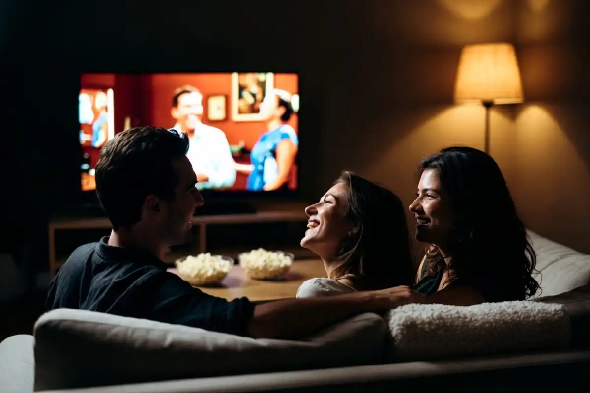 Friends laughing together while watching Amazon Prime comedy movies on a couch at home