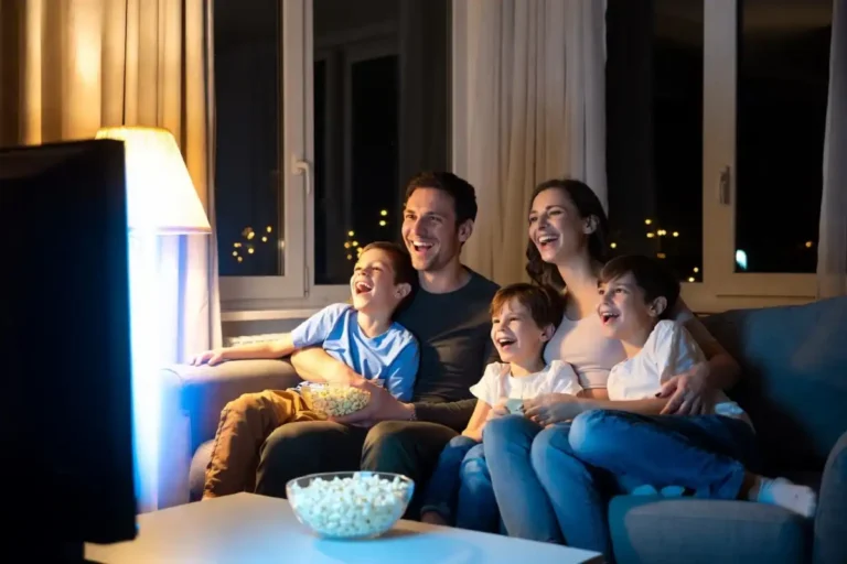 Family laughing together while watching a comedy film on the sofa at night