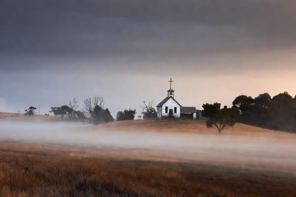 Leviticus Cast and Story scene mood with a misty rural Australian town and old church at dusk
