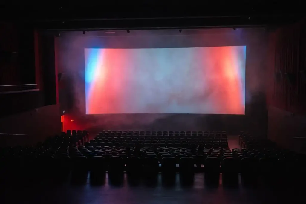 Shadowy theater seats facing a glowing screen with horror lighting